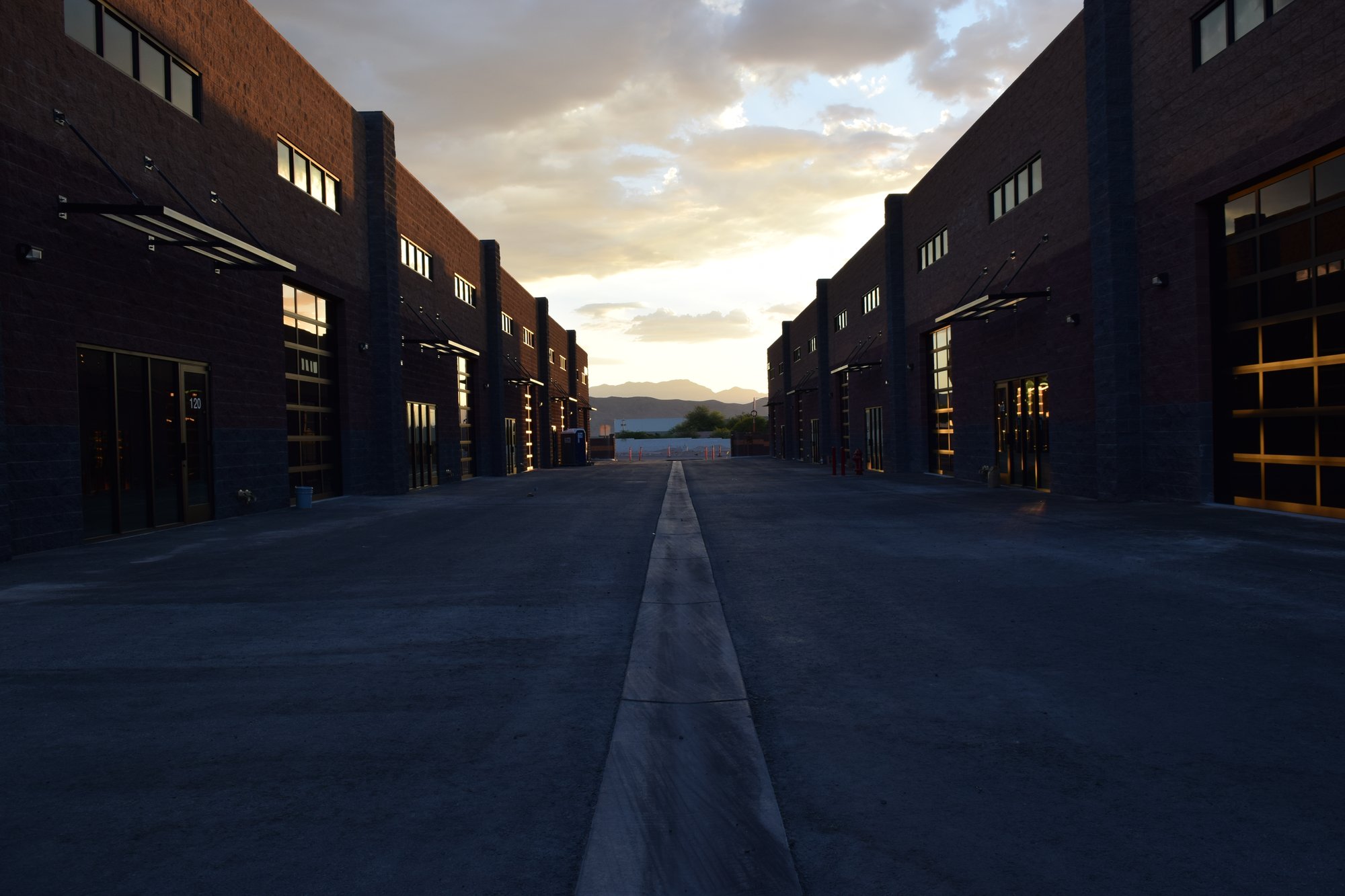 Dusk view down the drive between two buildings at The Stack Auto Lofts, with roll-up doors lit