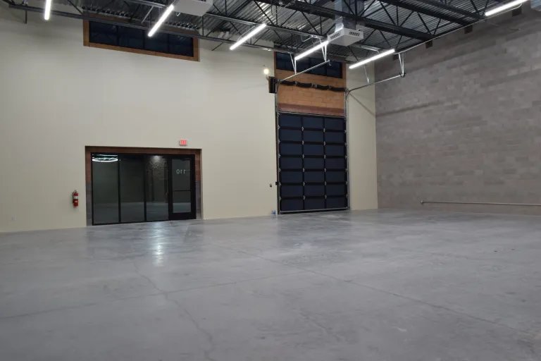 Empty unit at The Stack Auto Lofts showing a glass entry door and a tall roll-up door