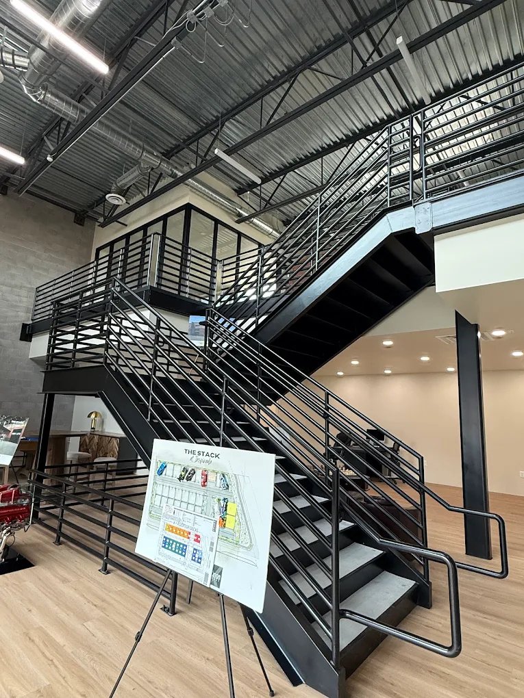 Steel staircase inside the clubhouse at The Stack Auto Lofts, with a site plan board on an easel